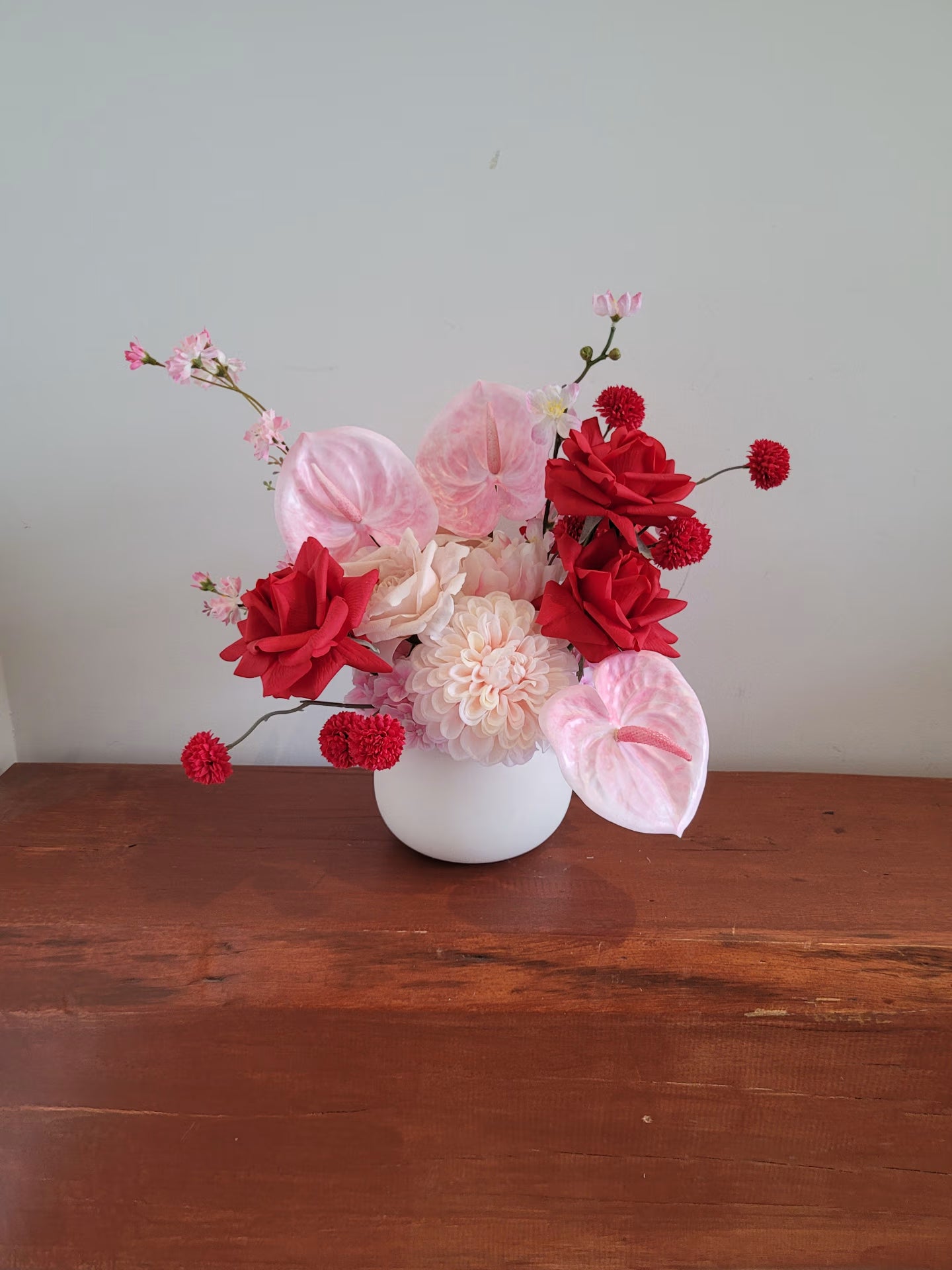 Distant photograph of a flower arrangement on a wooden surface
