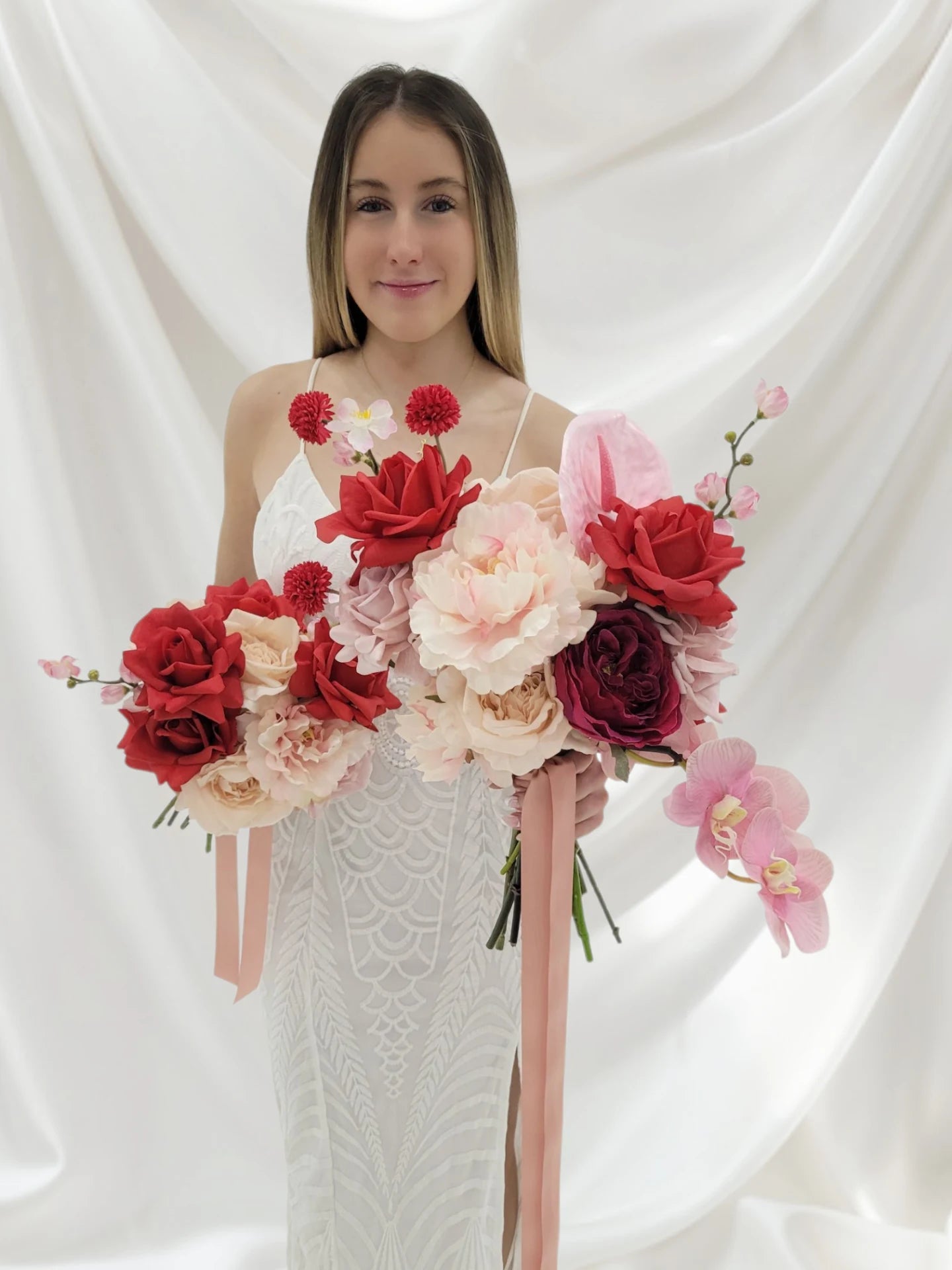 Woman holding a bouquet of red and pink flowers against a white background