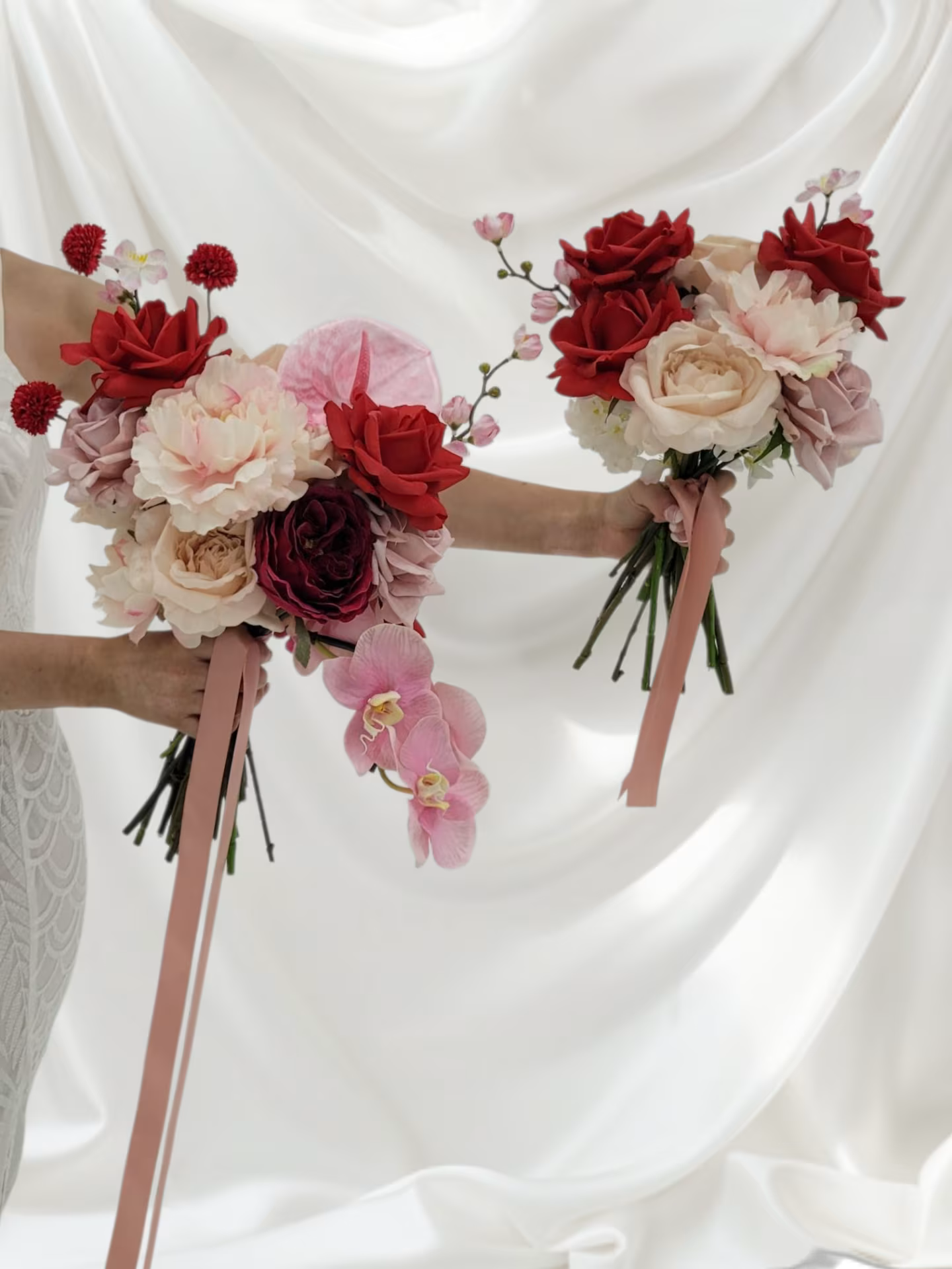 Two floral bouquets held by a person against a white curtain
