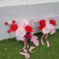 Wedding bouquets with red and pink flowers on a grassy surface.