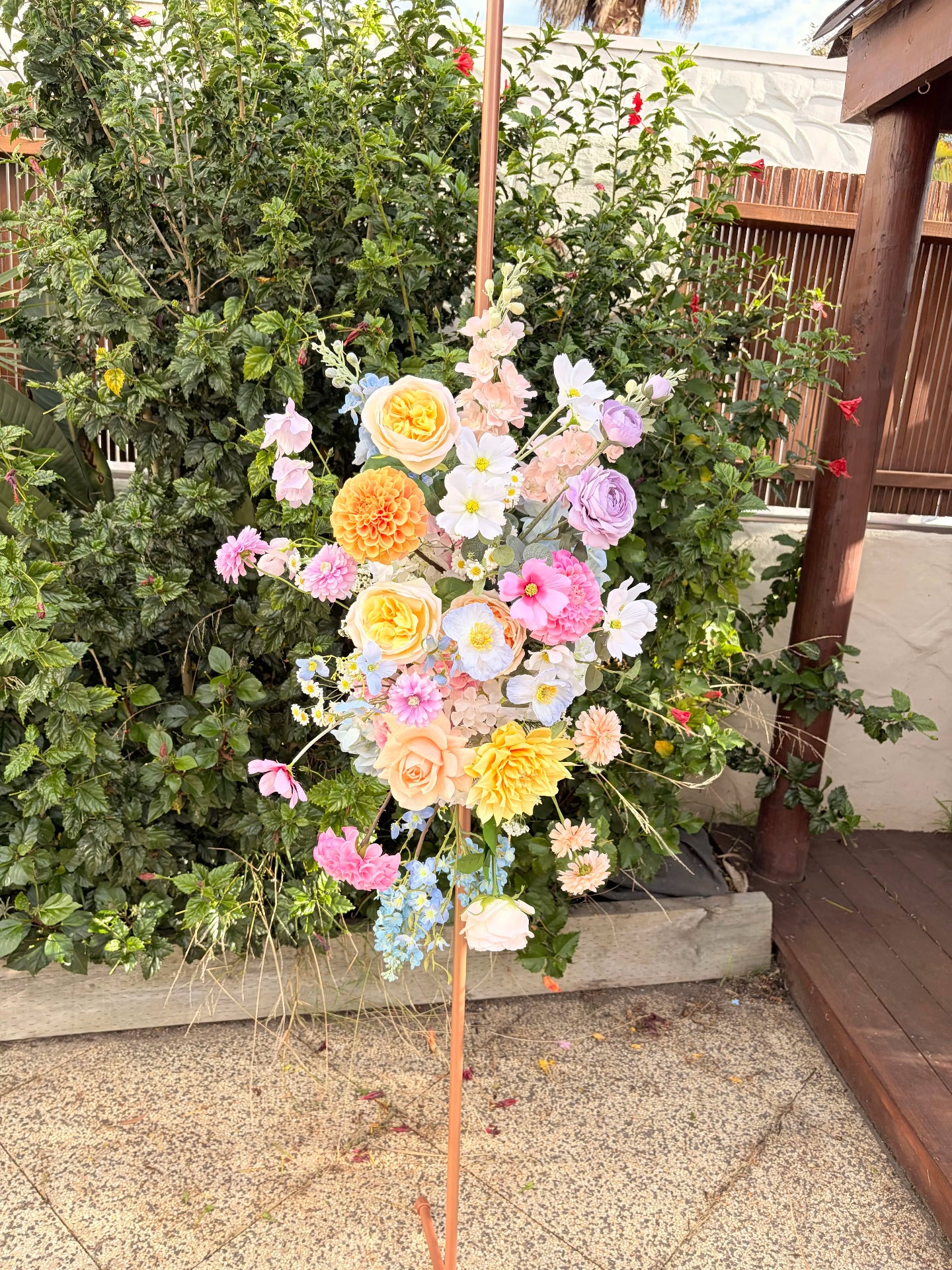 Colorful flower arrangement on a stand with greenery in the background