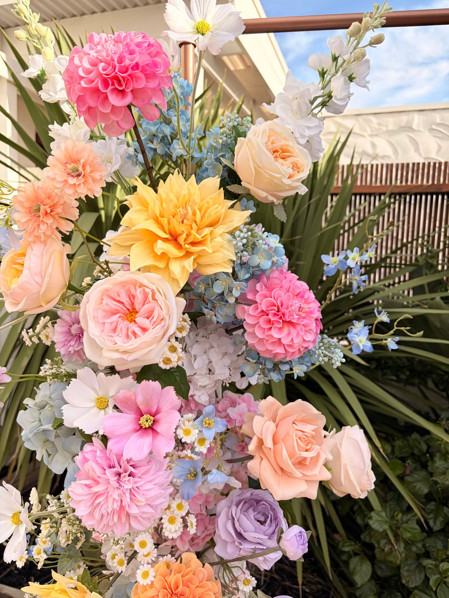 Colorful flower arrangement with pink, yellow, and white flowers in a garden setting.