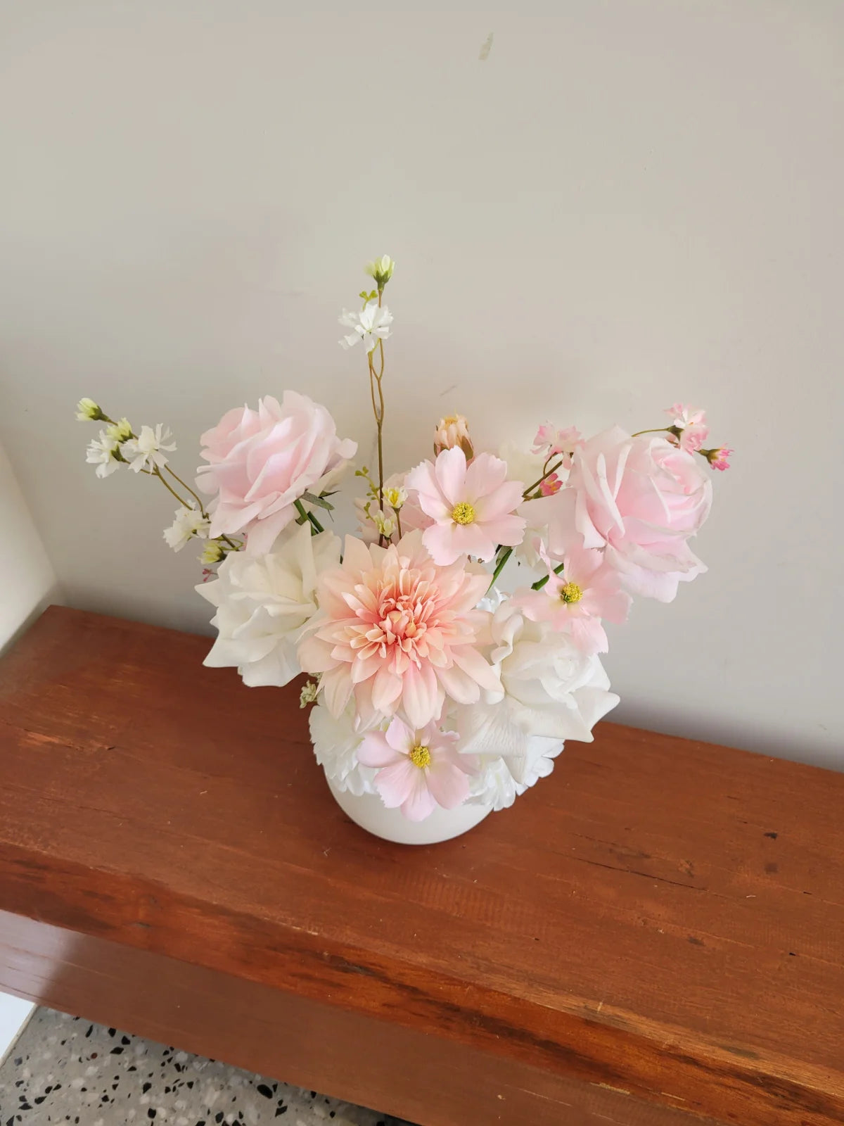 Vase with pink and white flowers on a wooden surface