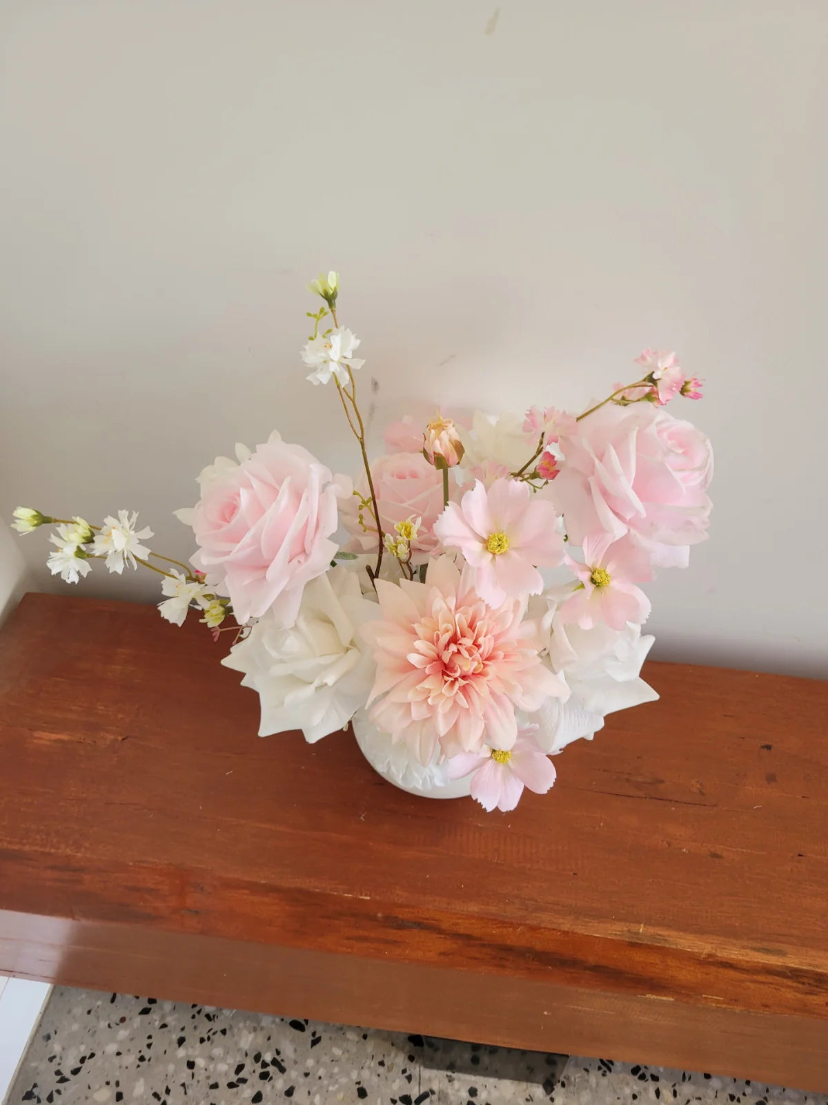 Bouquet of pink and white flowers in a vase on a wooden surface.