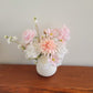 Pink and white silk flower arrangement in a white pot