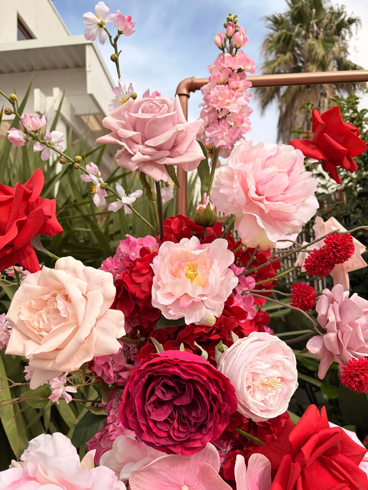 Close up of red and pink artificial flowers with dainty pink peonies