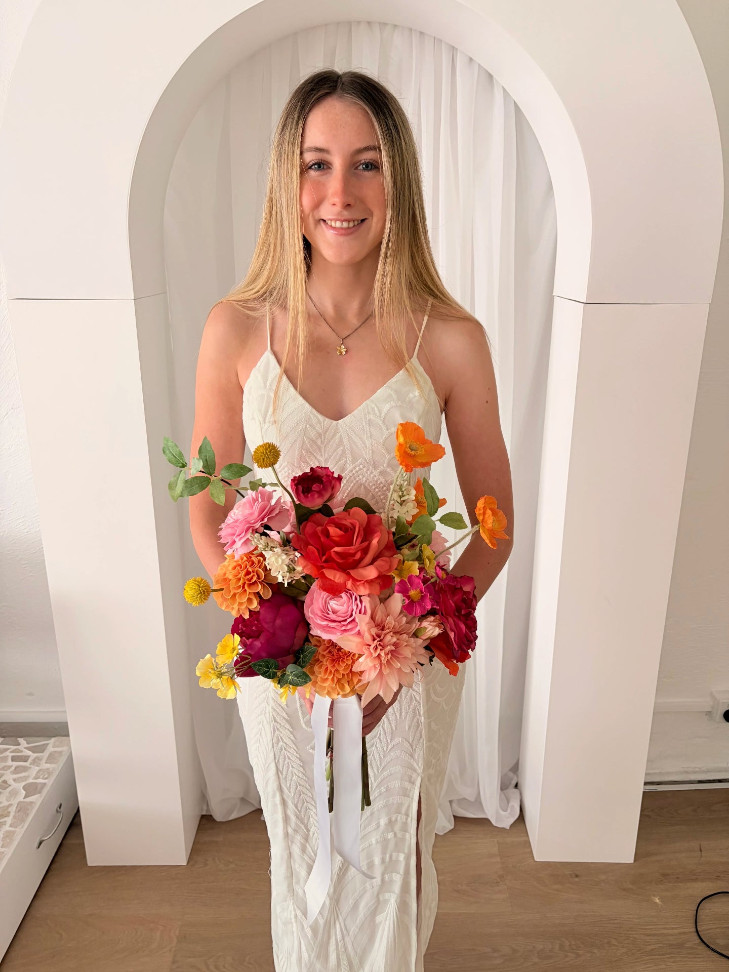 Woman holding a colorful wedding bouquet of flowers indoors.