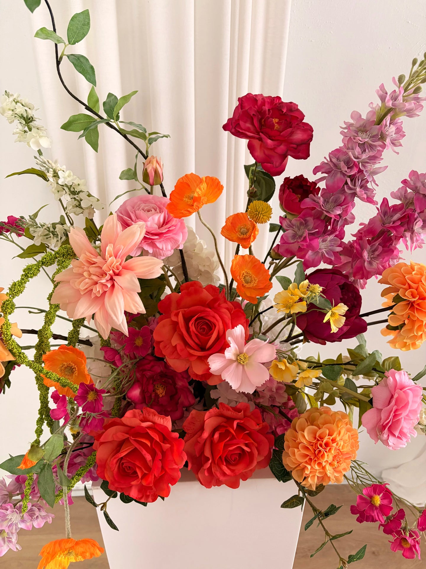 Artificial flower arrangement in a dainty whimsical style on a plinth in orange and pink tones