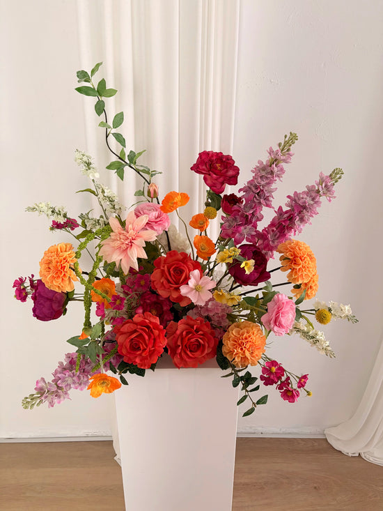 Bright and whimsical artificial flower arrangement on a wedding plinth