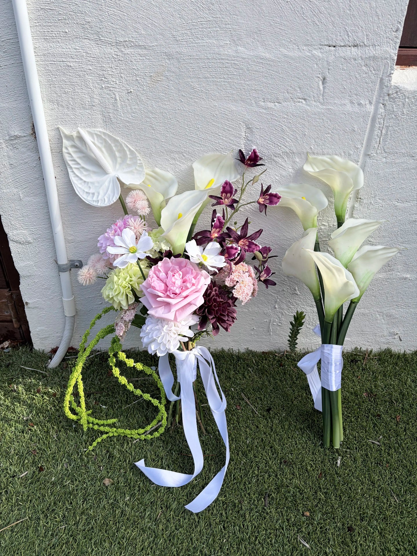 Modern bridal bouquet in pink, white and burgundy with calla lilies next to a bouquet of white calla lilies only.