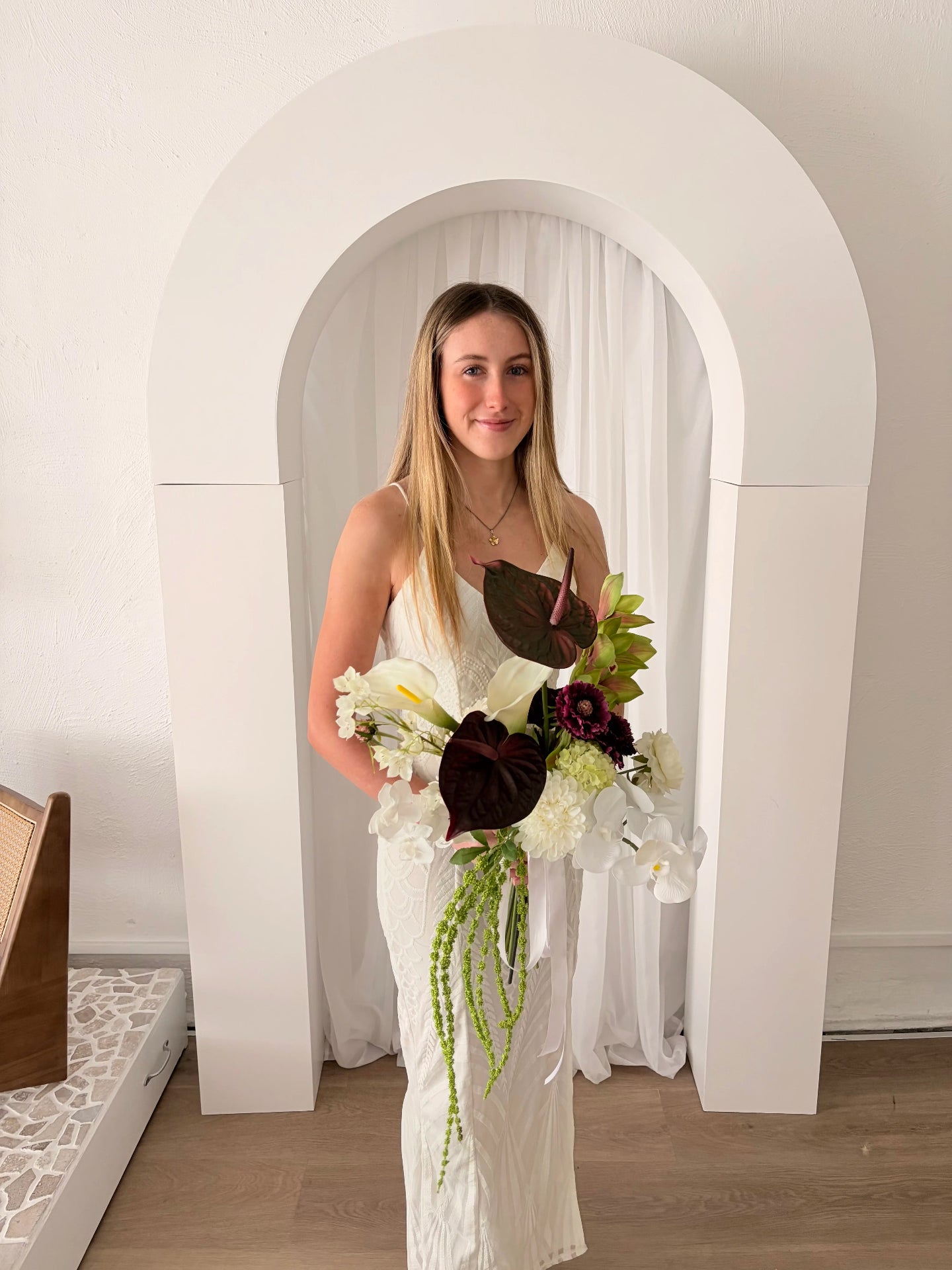 Woman holding a sculptural bouquet of flowers in a room with an archway.