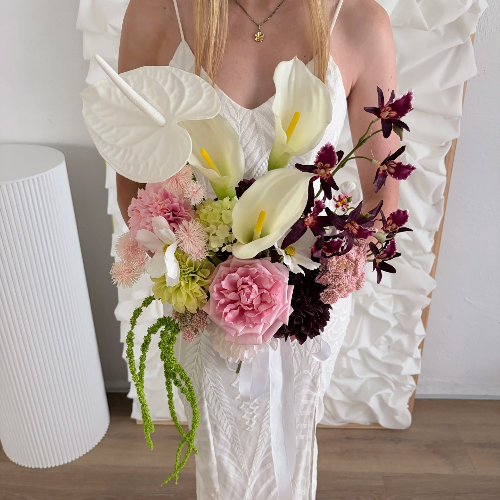 Bouquet of modern artificial flowers held by a person in a white dress with a white background