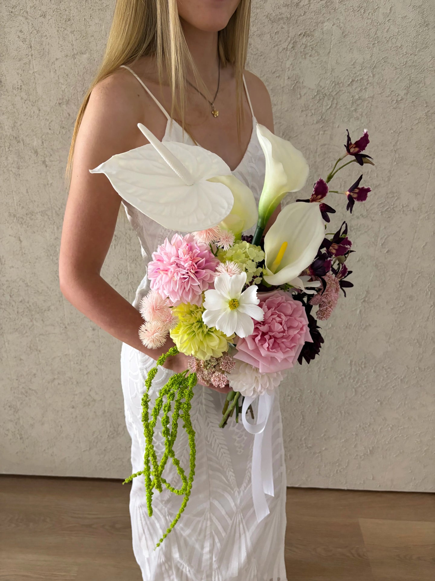 Woman holding a bouquet of artificial wedding flowers against a neutral background