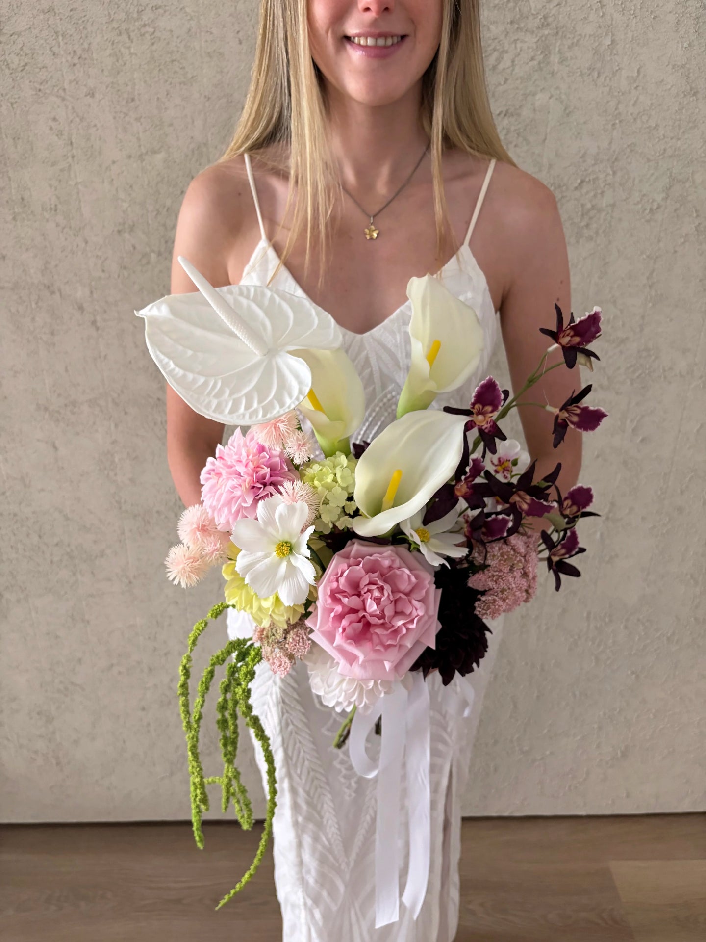 Woman holding a sculptural bouquet of wedding flowers against a neutral background