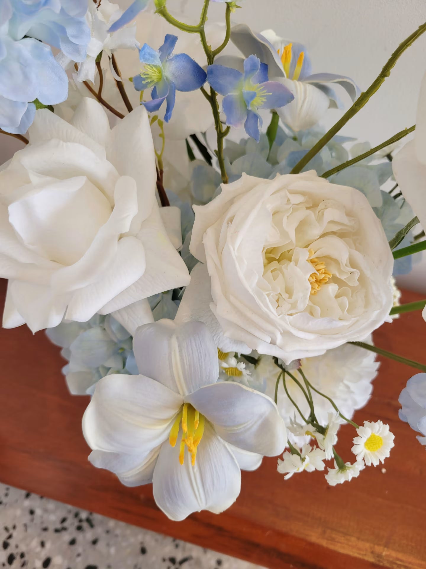 Close up of a white artificial David Austin rose in a flower arrangement of blue and white flowers