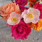 Close up of peach coloured poppies amongst hot pink and orange roses