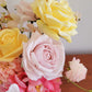 Side view of a yellow real touch rose next to a blush pink rose