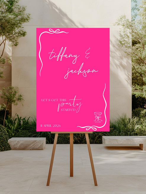 Pink wedding sign on an easel outdoors