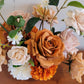 Close up of rustic style artificial flower arrangement featuring a large terracotta rose