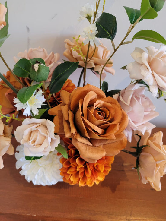 Close up of rustic style artificial flower arrangement featuring a large terracotta rose