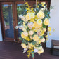Floral arrangement with yellow and white flowers on a wooden deck.