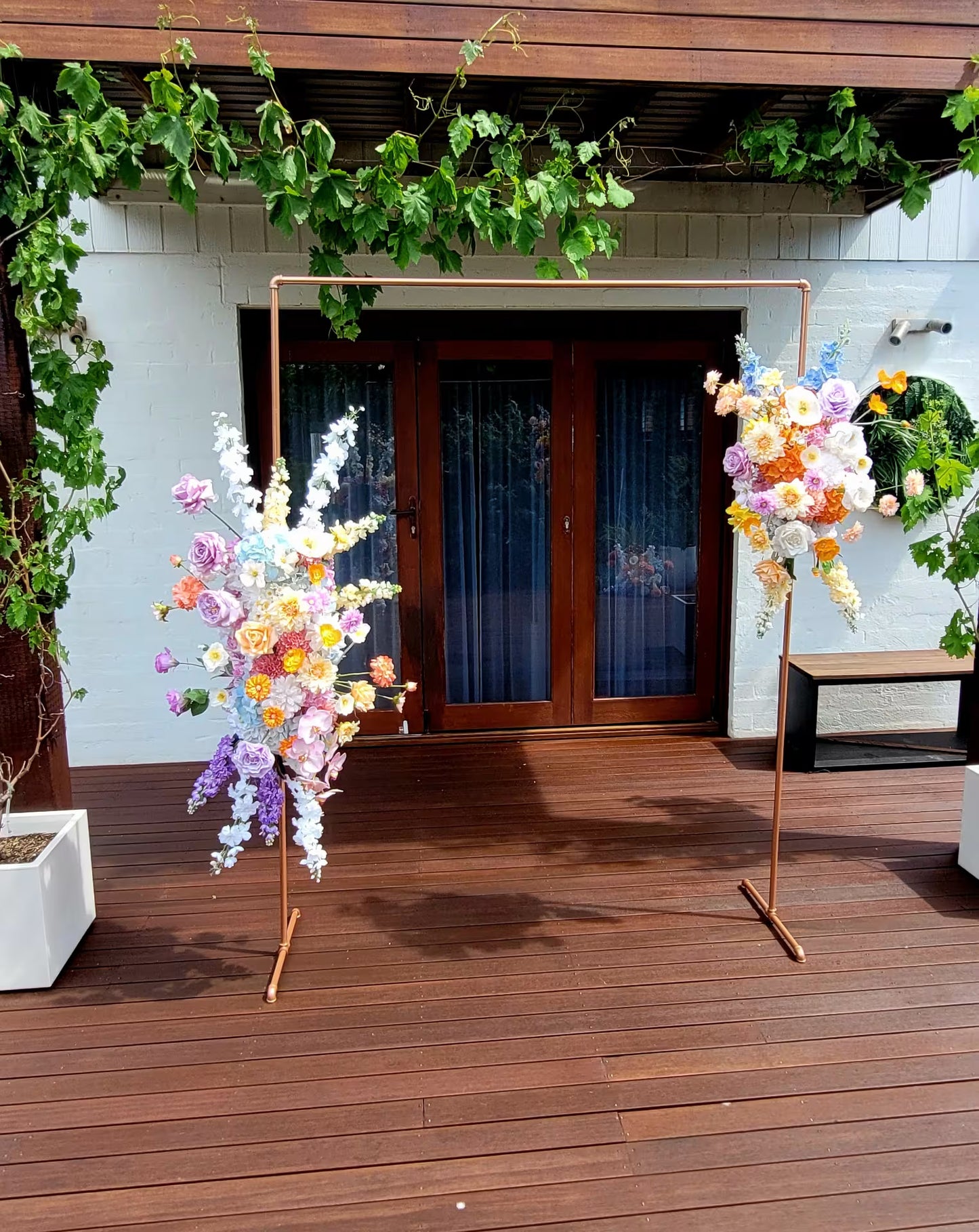 Arbour arrangements on a wooden deck with wooden doors  in the background