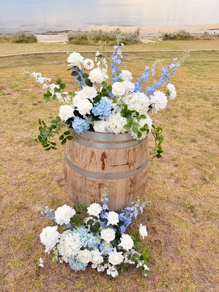 Floral arrangement in a wooden barrel on a grassy field