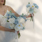 Woman holding two wedding bouquets of white and blue flowers against a plain background