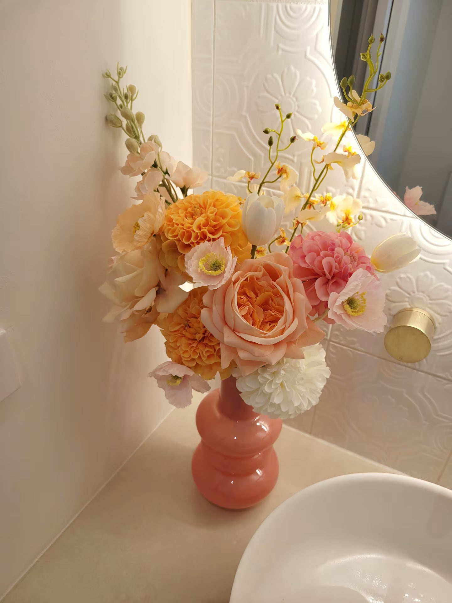 Floral arrangement in a pink vase on a bathroom counter