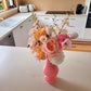 Pink vase with flowers on a kitchen counter