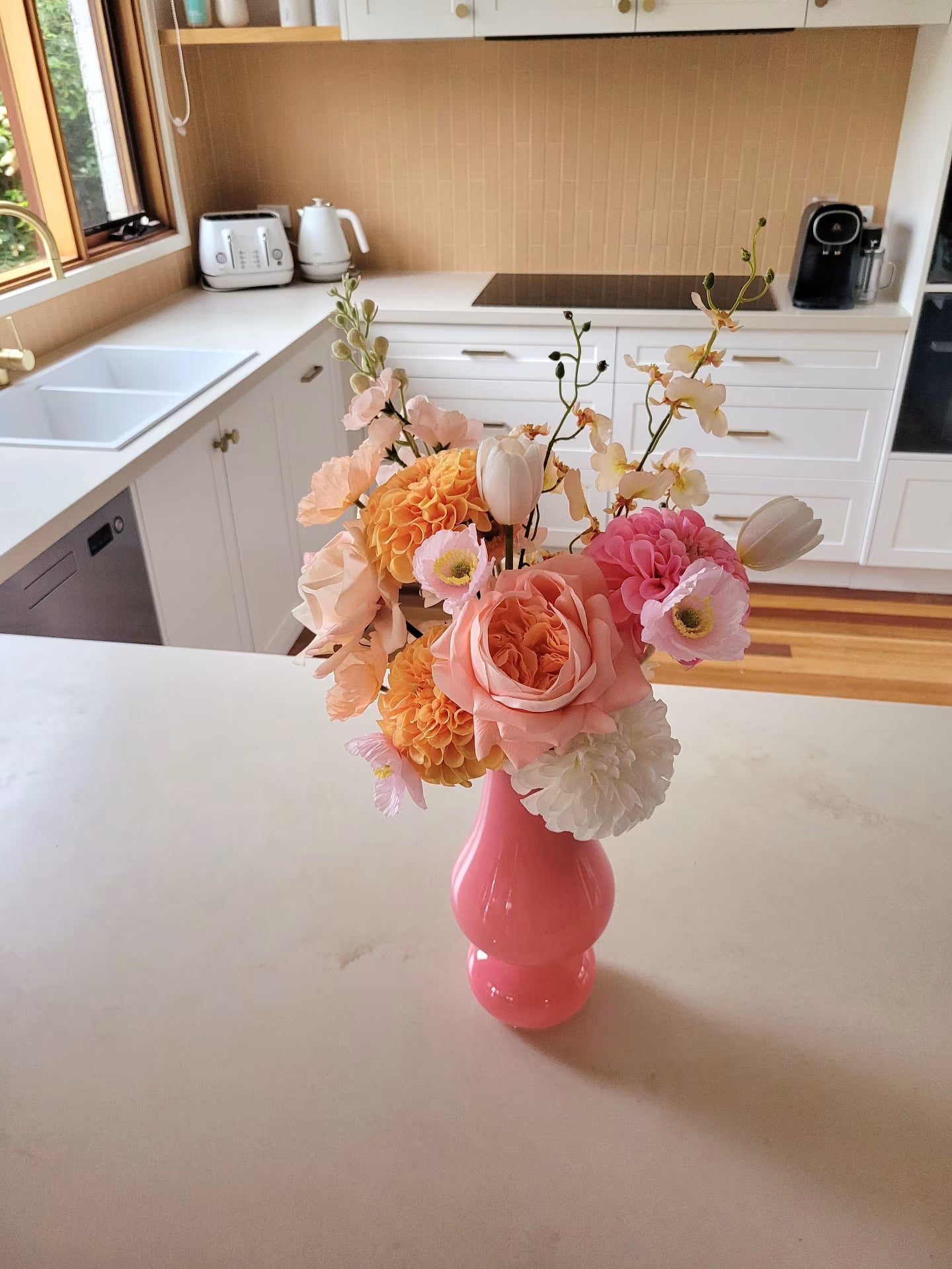 Pink vase with flowers on a kitchen counter