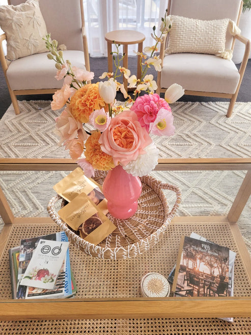 Orange and light pink floral arrangement on a coffee table