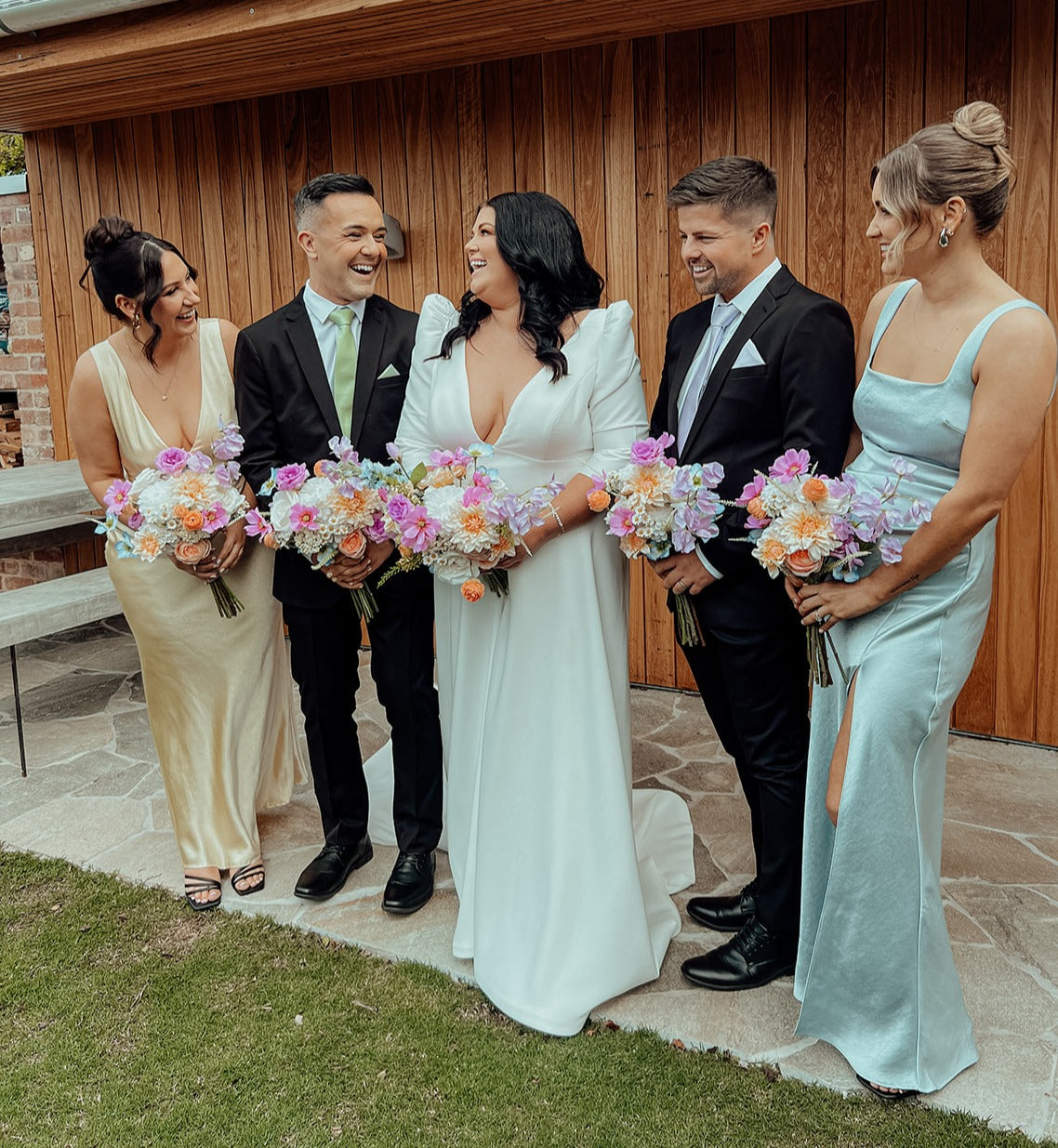 Bridal party with bridesmaids and bridesmen holding pastel wedding bouquets