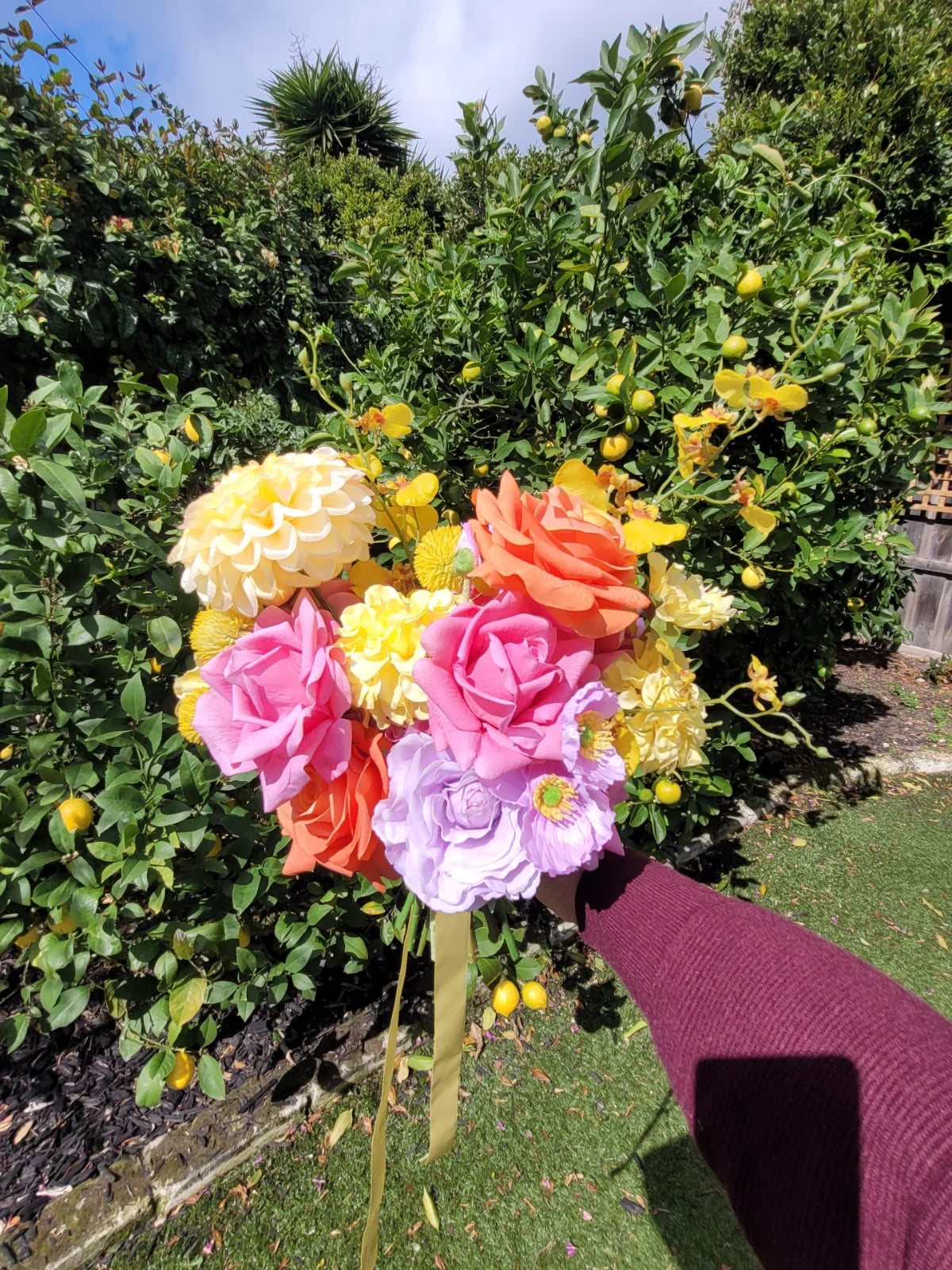 Bouquet of colorful flowers held by a person in a garden setting