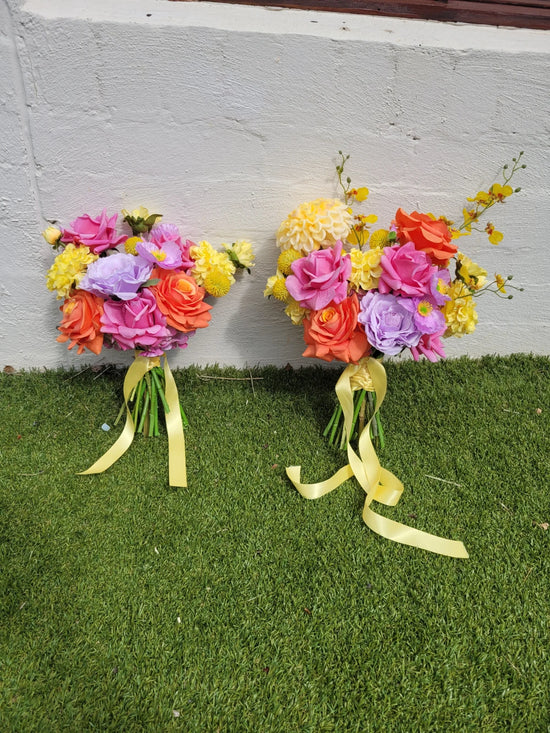 Two colorful flower bouquets with ribbons on a grassy surface.