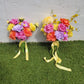 Two floral bouquets with colorful flowers and ribbons on a grassy surface.