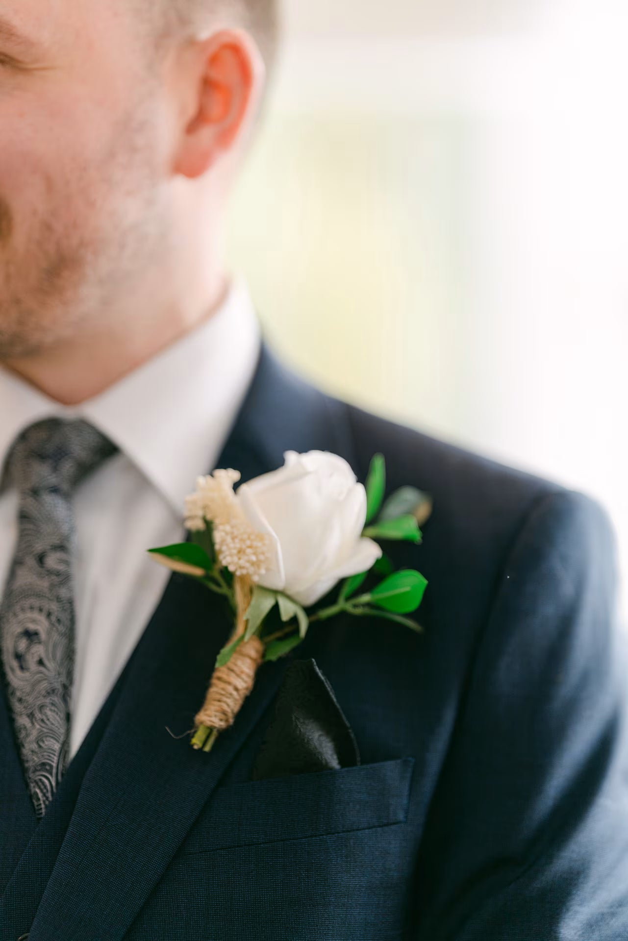 Close up of groom wearing a white rose buttonhole