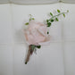 Pink rose boutonniere on a white quilted surface