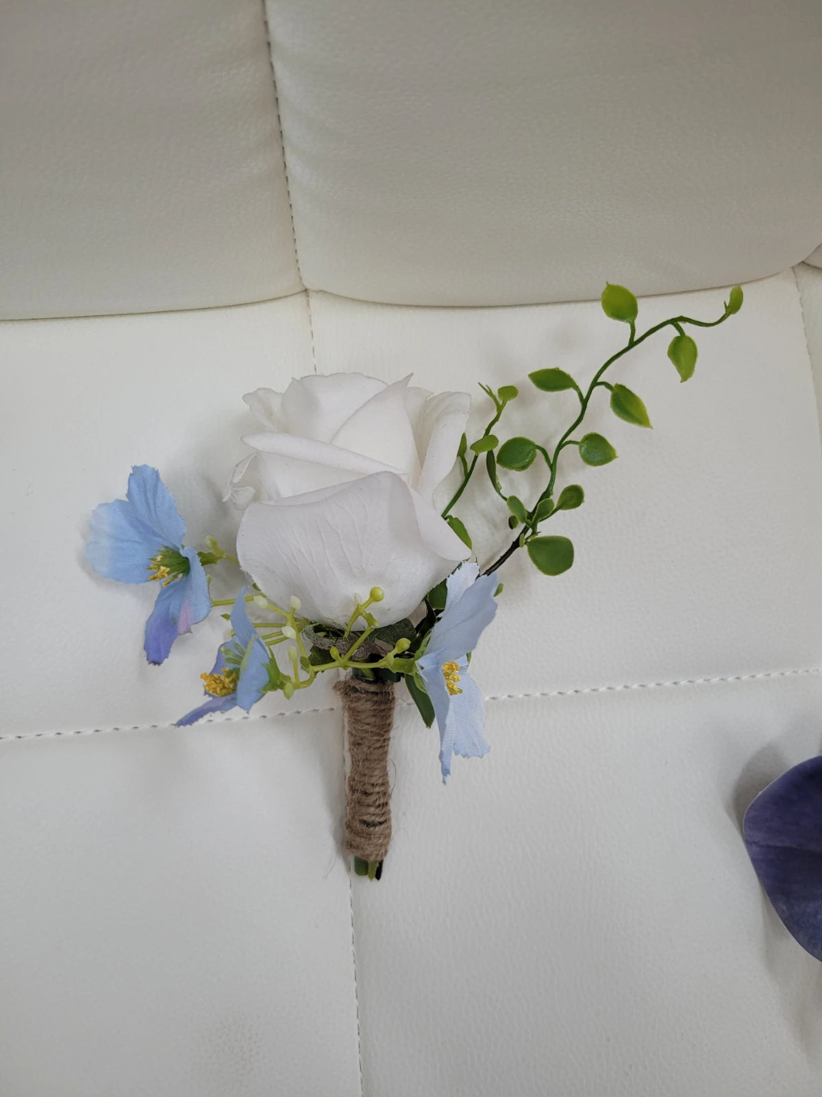 White flower boutonniere with blue accents on a white background