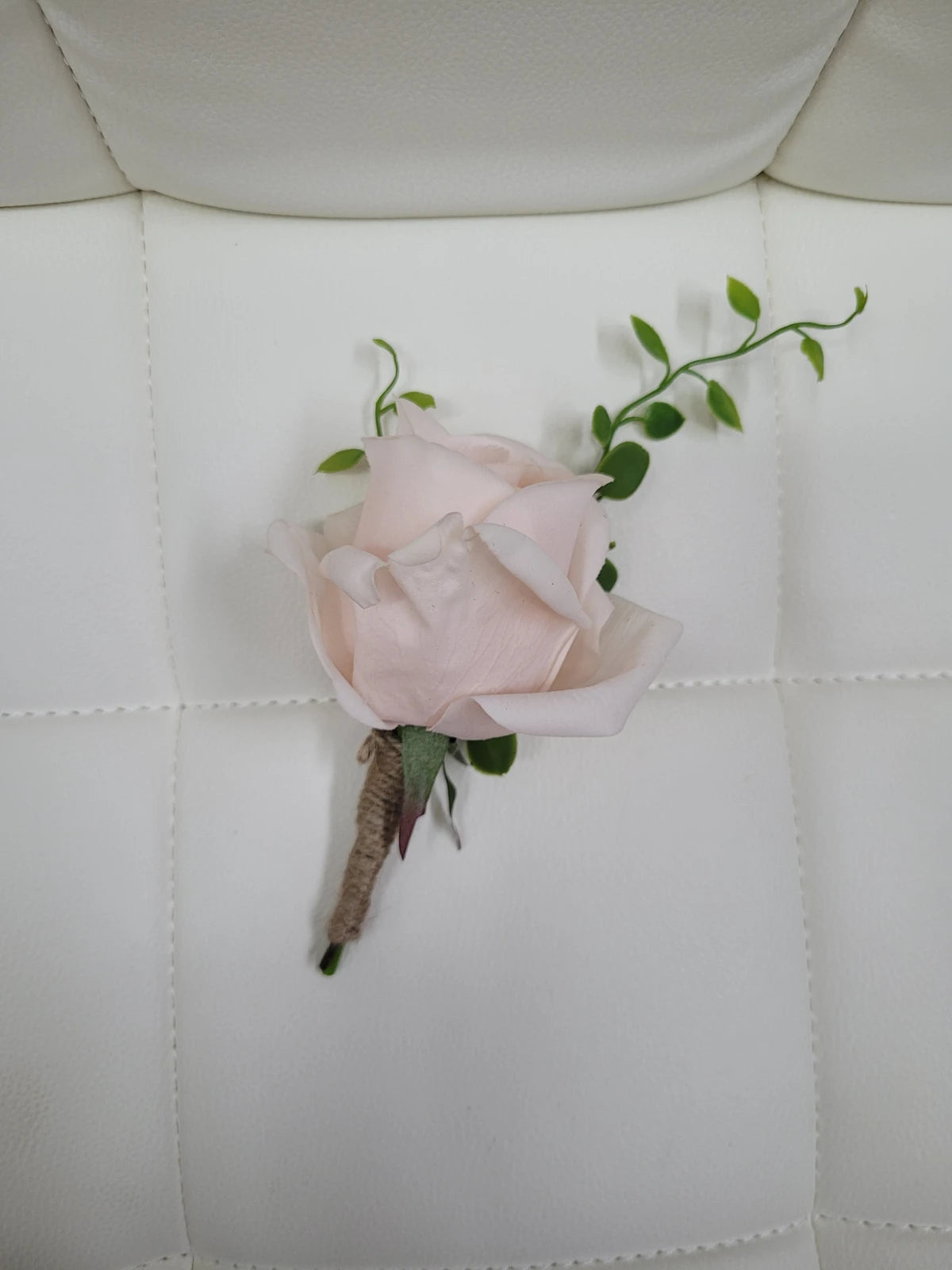 Pink flower buttonhole on a white quilted surface