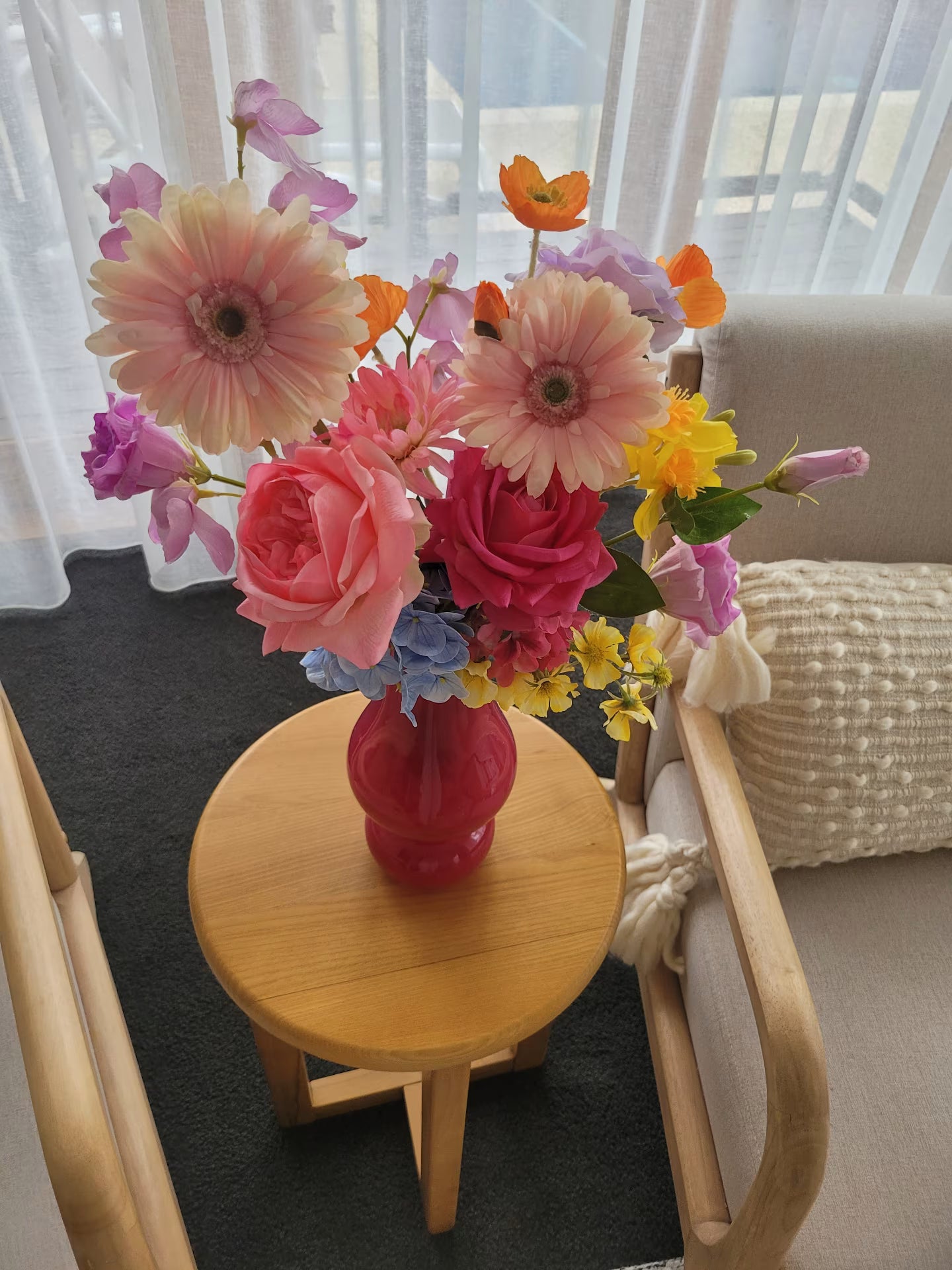 Colorful flower arrangement in a pink vase on a wooden table with a blurred background