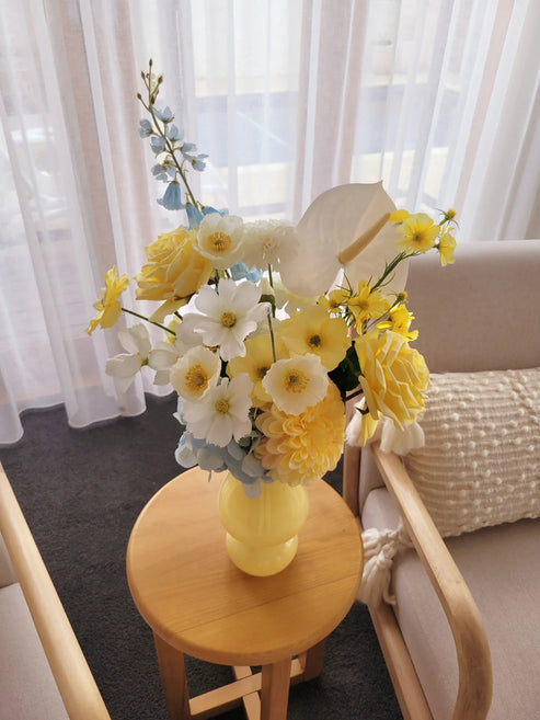 Flower arrangement with yellow, white and blue flowers on a side table 