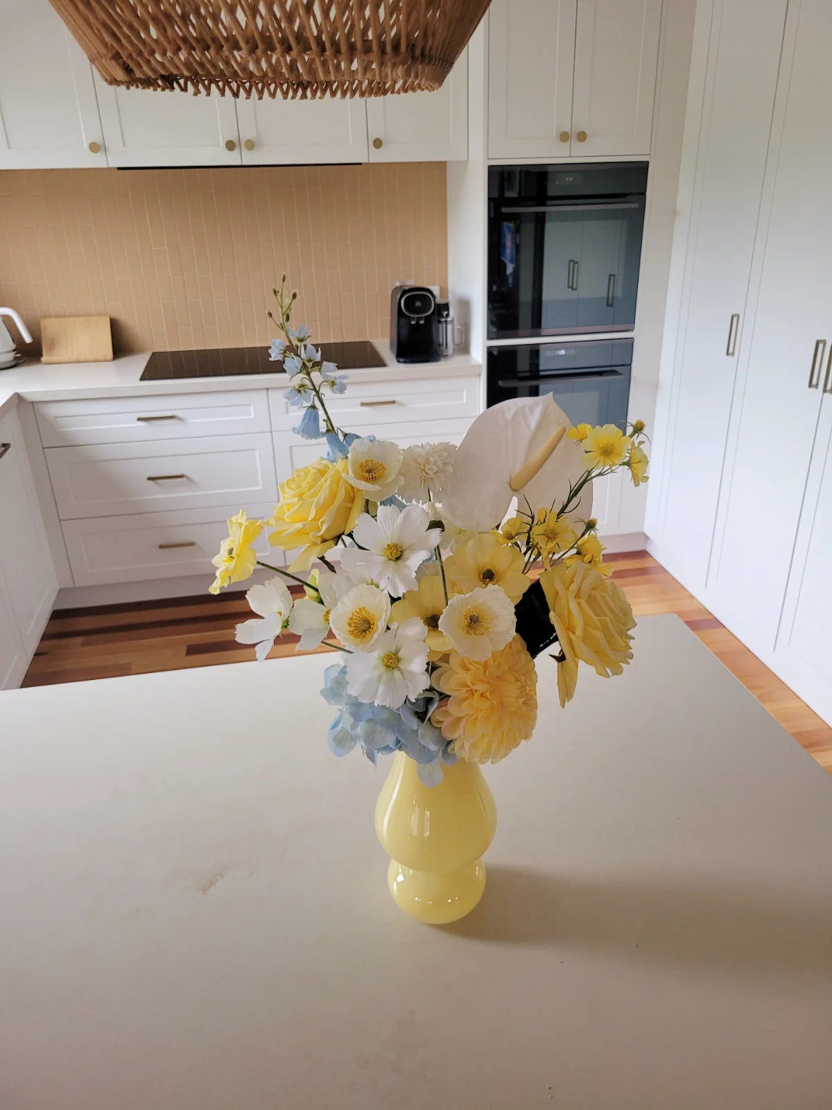 Yellow vase with flowers on a kitchen counter