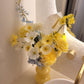 Yellow and white flowers in a yellow vase on a bathroom counter.