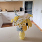 Yellow vase with flowers on a kitchen counter