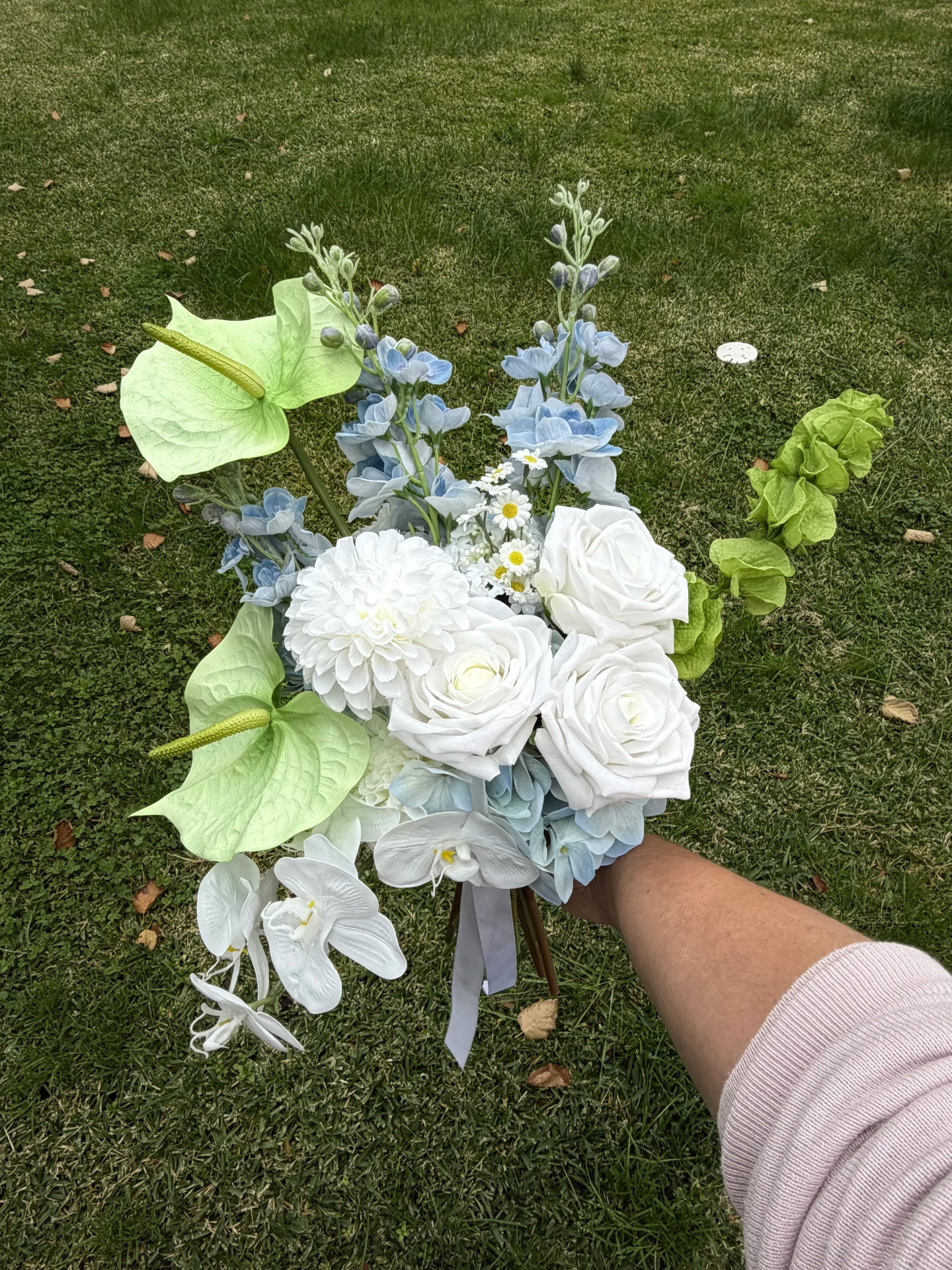 Bouquet of flowers held by a person on grass