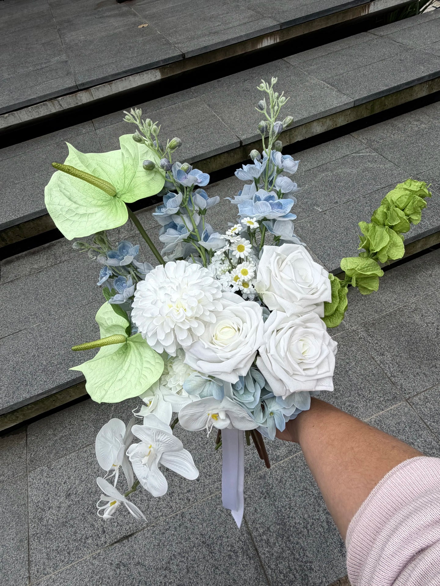 Bouquet of flowers held by a person on stone steps