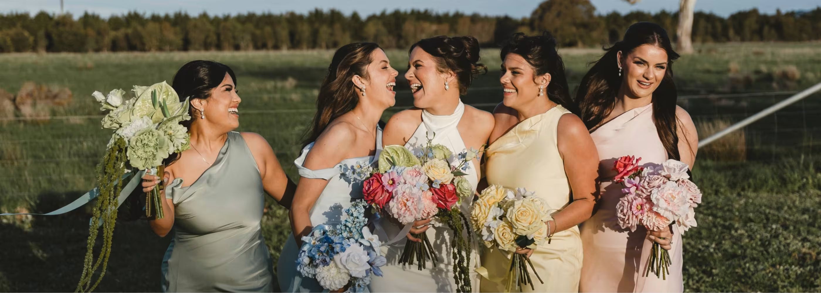 Bridal party standing outdoors with floral bouquets in a field