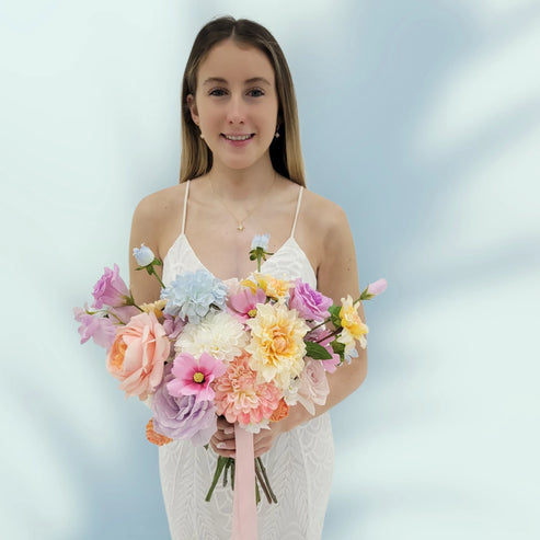 Woman holding a bouquet of pastel flowers against a light blue background