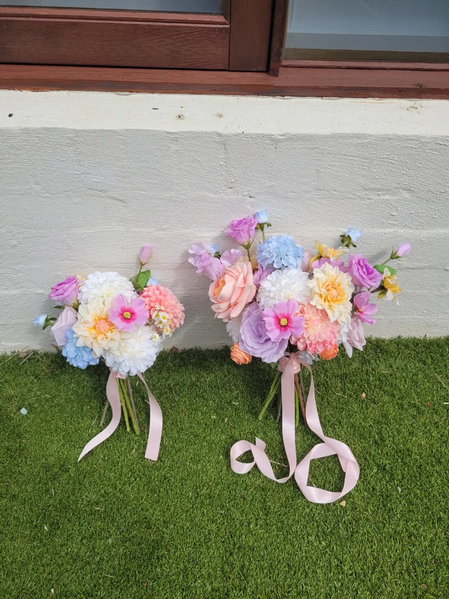 Two floral bouquets with ribbons on a grassy surface.